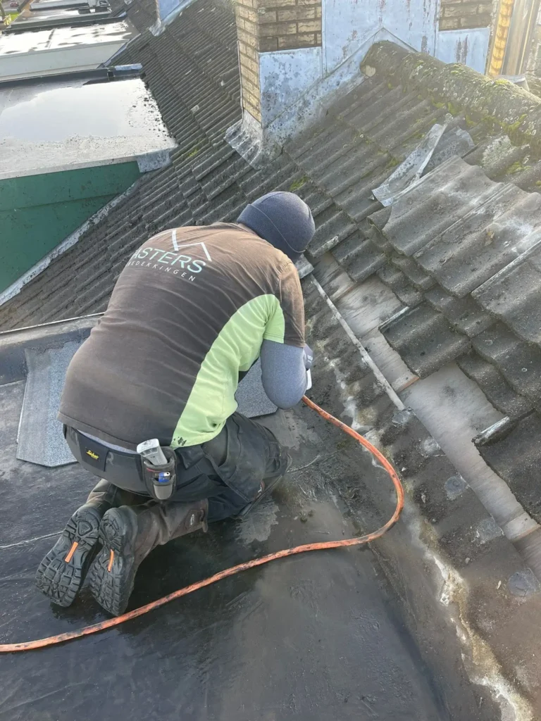Onderhoud aan bitumen dakbedekking door vakman op plat dak
