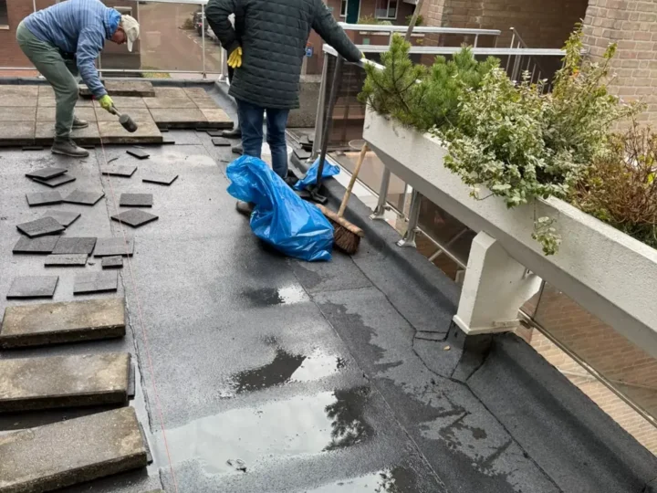 Bewoners van VvE Toutenburg helpen de tegels terug te leggen op het nieuwe galerijdak