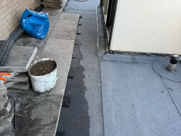 Nieuwe dakbedekking langs de galerij, de tegels liggen nog opzij