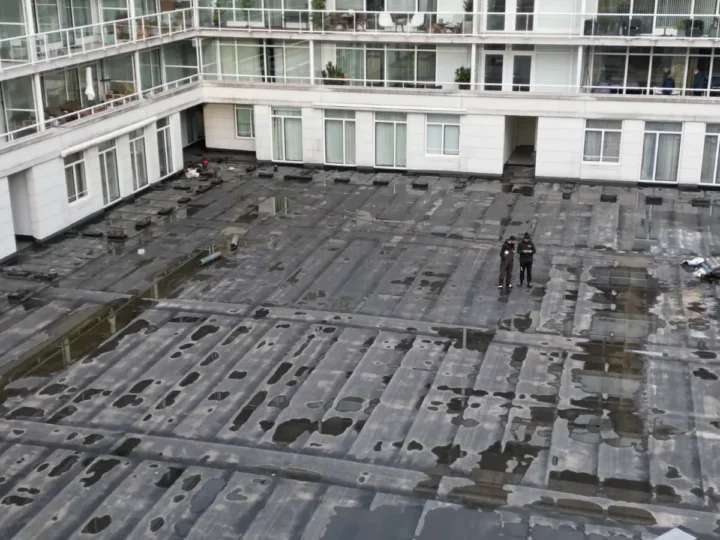 Dronefoto van het dak tijdens het werk, met twee dakdekkers