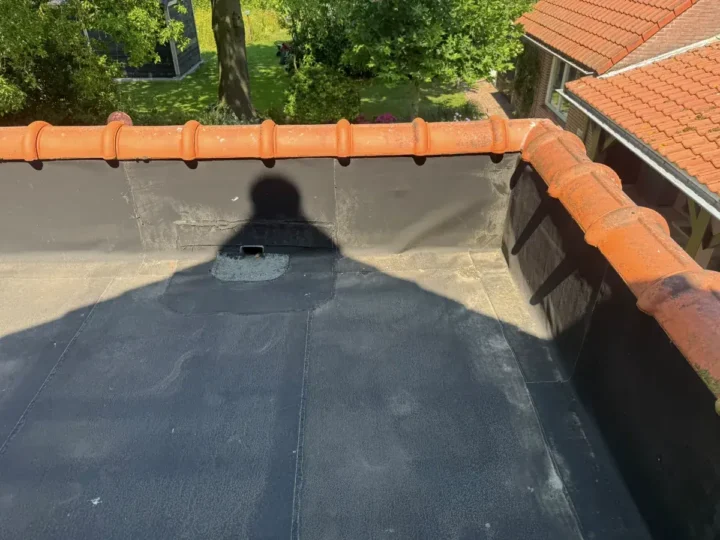 Het oude platte dak met een eerdere reparatie rond de afvoer