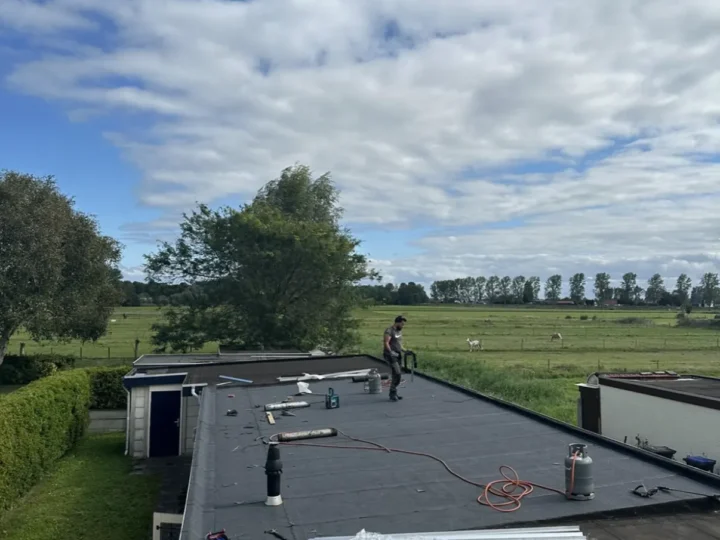 Overlagen van het lange platte dak, met de polder op de achtergrond